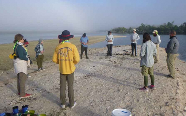 a group of families stand on a beach during a canoeing exercise on an outward bound trip